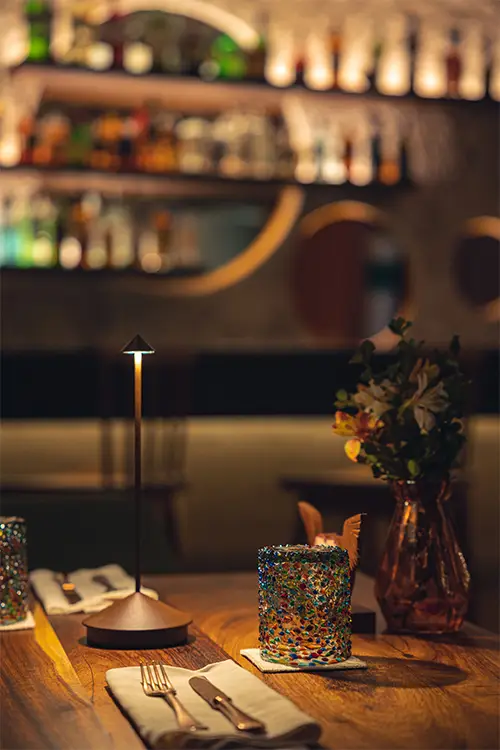 Elegant fine dining setting at La Casa de la Playa with warm ambient lighting, artisanal glassware, and intimate upscale restaurant atmosphere in Riviera Maya.