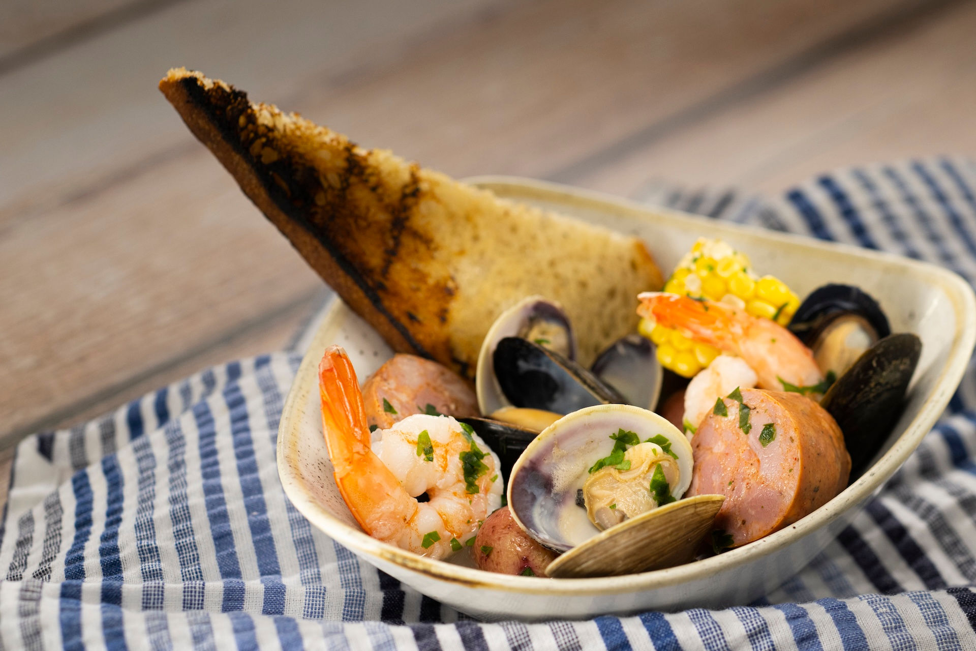Seafood bake with shrimp, clams, mussels, sausage, potatoes, and corn from EPCOT Flower & Garden Festival booth at Walt Disney World, showcasing popular Disney festival savory dishes and personalized Disney trip planning support from travel advisor Brandi Parker.
