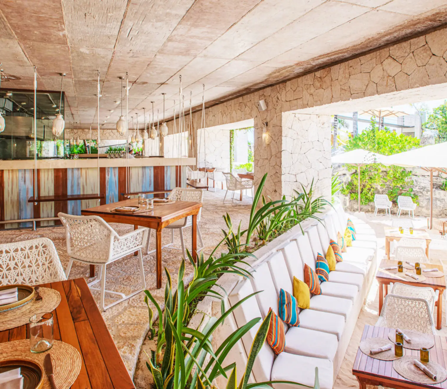 Open-air restaurant with stone walls, neutral decor, and lounge seating at Hotel Xcaret Mexico, highlighting beachfront dining, relaxed luxury, and family-friendly all-inclusive resort experience in Riviera Maya.