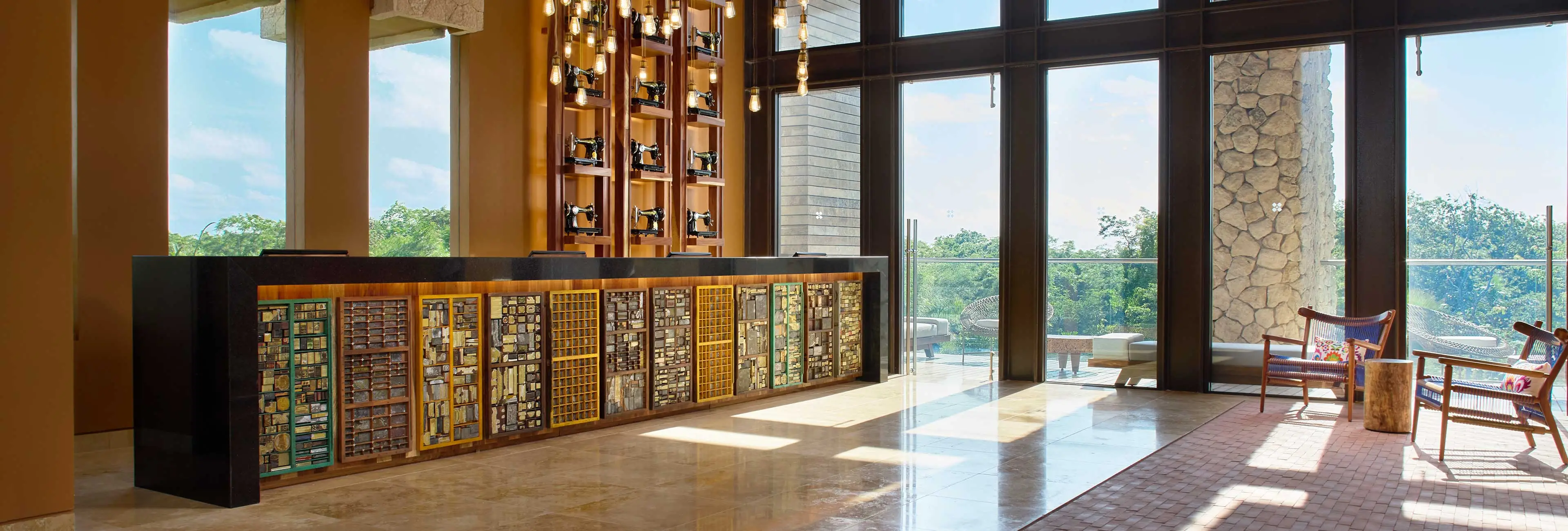Reception desk with artisan material displays and textile-inspired design at Hotel Xcaret Arte, highlighting Casa del Diseño craftsmanship, immersive art concept, and adults-only all-inclusive resort in Riviera Maya.