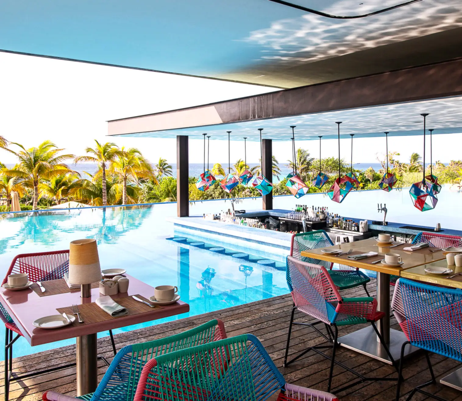 Infinity pool swim-up bar with colorful hanging lanterns and ocean views at Hotel Xcaret, showcasing adults-only luxury, rooftop dining, and Riviera Maya all-inclusive resort ambiance.