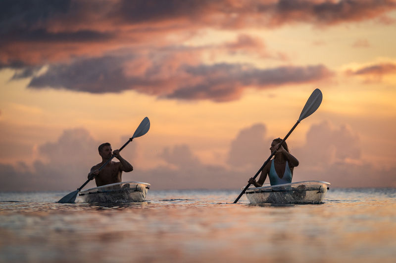 Couple kayaking in clear water at sunset during a romantic Sandals resort ocean activity.