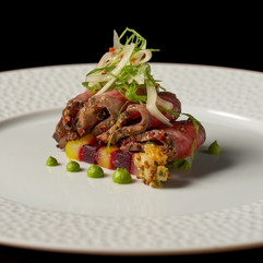 Plated gourmet entrée at Disneyland Napa Rose restaurant featuring seared beef or tuna over layered vegetables with mustard seed sauce and microgreens, showcasing upscale fine dining cuisine at Disneyland Resort.