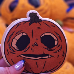 Halloween Horror Nights pumpkin-shaped dessert cookie with spooky face design held in hand, themed seasonal treat at Universal Orlando.