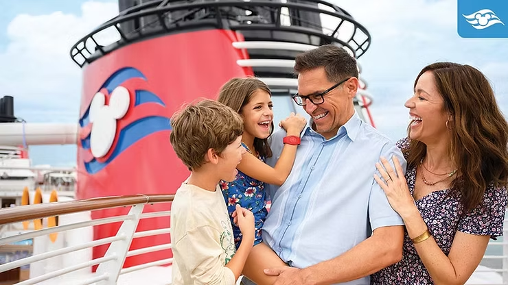 A family laughs together on the deck of a Disney Cruise Line ship with the iconic red funnel in the background, capturing a relaxed family moment, onboard cruising atmosphere, and the joy of a Disney cruise vacation at sea.