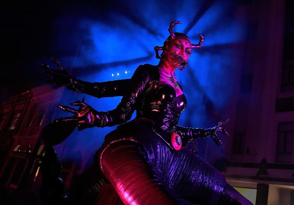 Halloween Horror Nights scare actor in elaborate creature costume under dramatic red and blue lighting creating an intense immersive horror scene.