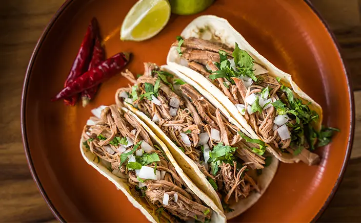 Cochinita pibil tacos with pickled onions and lime at Hotel Xcaret Arte, showcasing authentic Mexican cuisine, elevated dining, and all-inclusive culinary experiences in Riviera Maya.
