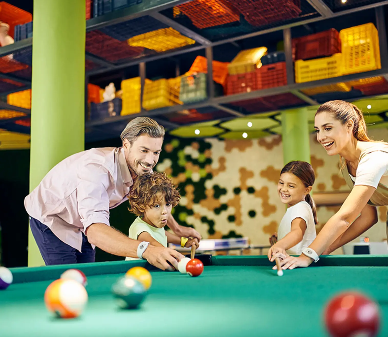 Hotel Xcaret Mexico family game room with pool table and colorful modern design, featuring parents and kids playing together, showcasing family-friendly all-inclusive entertainment and indoor activities.