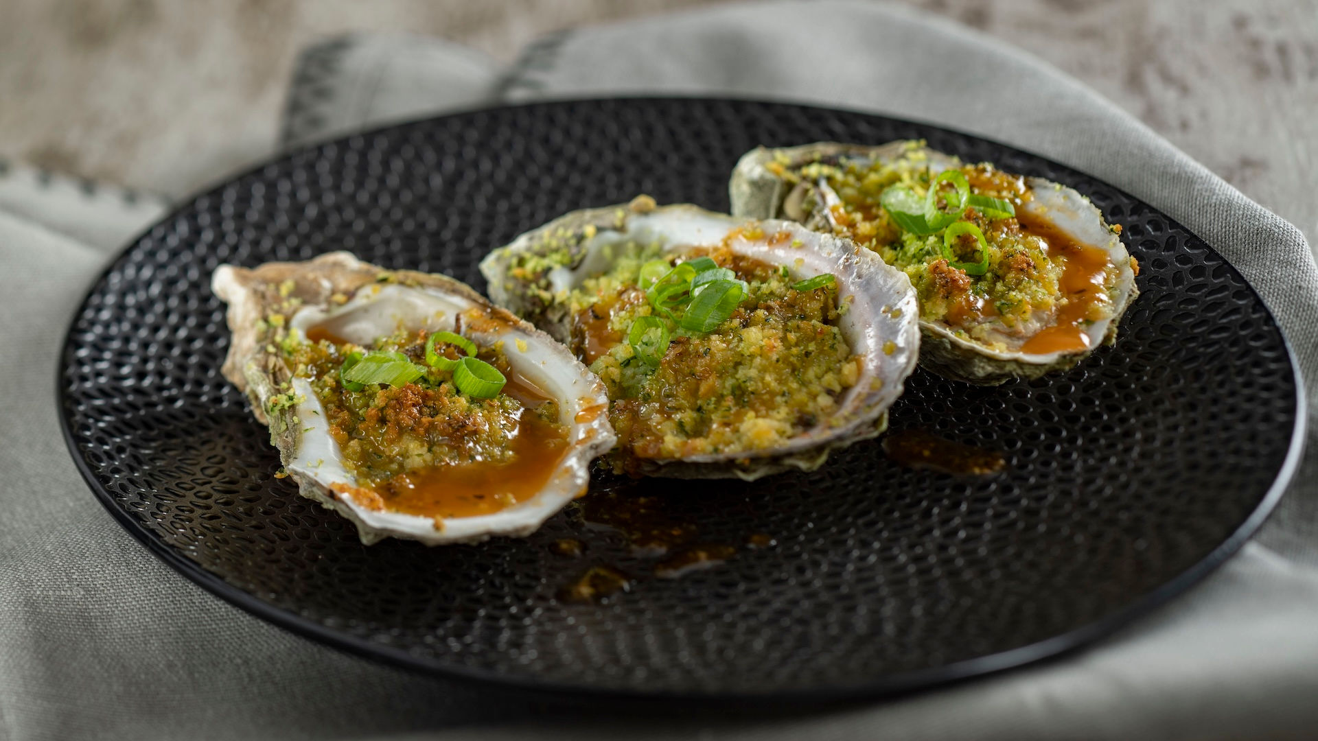 Fresh oysters on the half shell with garnish at EPCOT International Flower & Garden Festival booth, representing premium seafood options and globally inspired Disney World festival menu offerings.