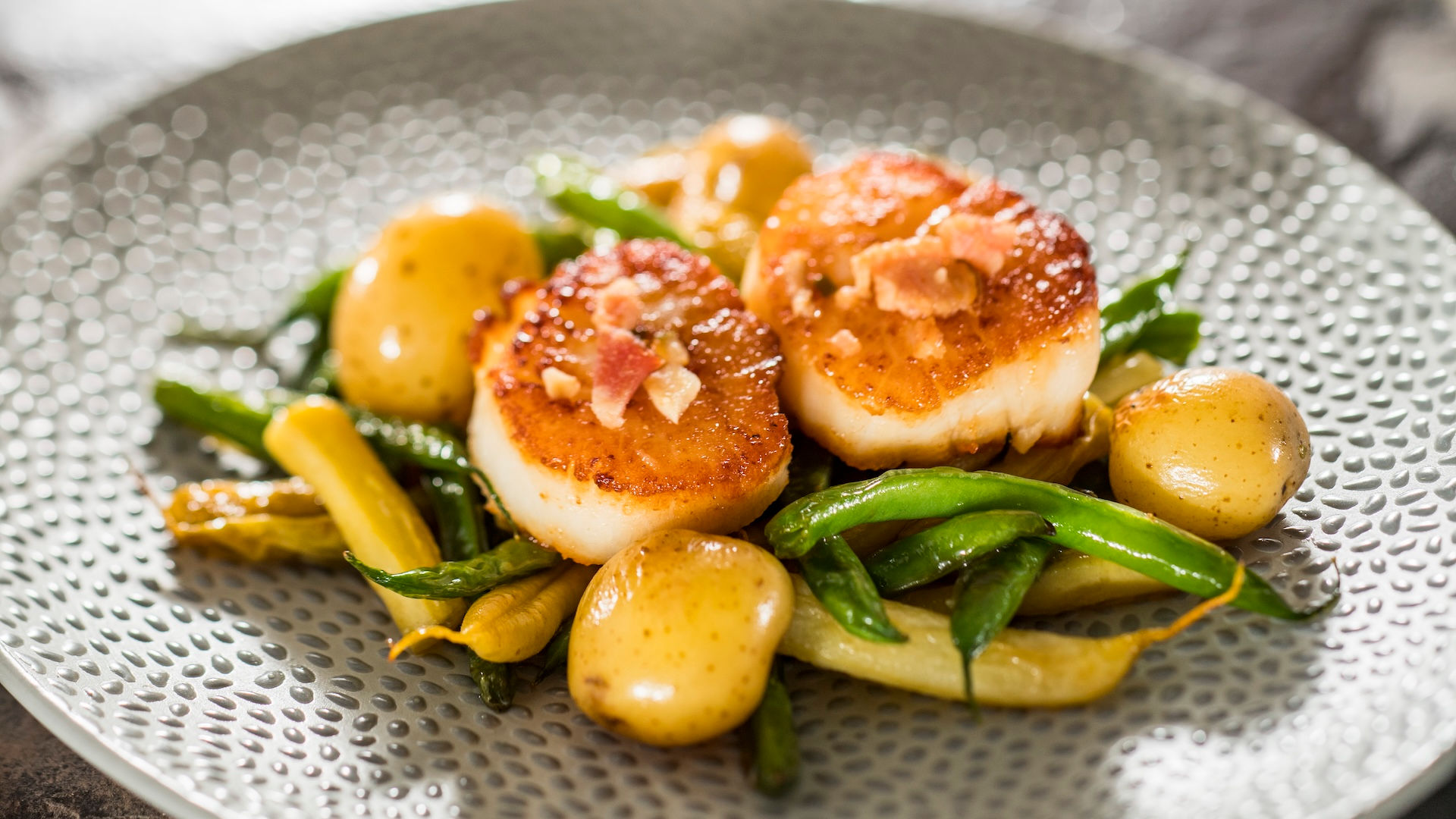“Seared scallops with green beans and potatoes at EPCOT International Flower and Garden Festival Outdoor Kitchen, a gourmet Walt Disney World festival entrée featured in Disney vacation planning recommendations by travel advisor Brandi Parker.”