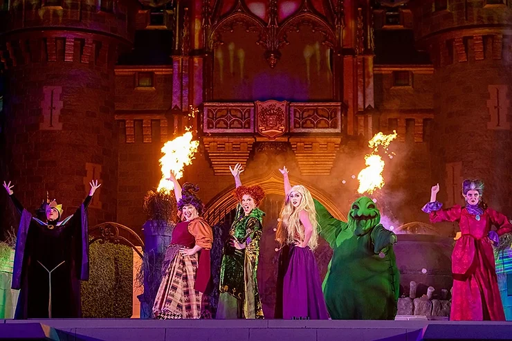Disney villains including the Sanderson Sisters, Oogie Boogie, and Maleficent performing on the Cinderella Castle stage during Hocus Pocus Villain Spelltacular.