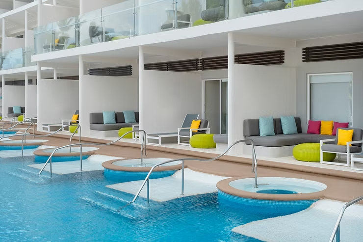 Modern all-inclusive resort swim-up suites featuring private plunge pools, in-water loungers, and shaded patio seating with contemporary furnishings, highlighting a luxury adults-friendly resort experience designed for relaxation and comfort.