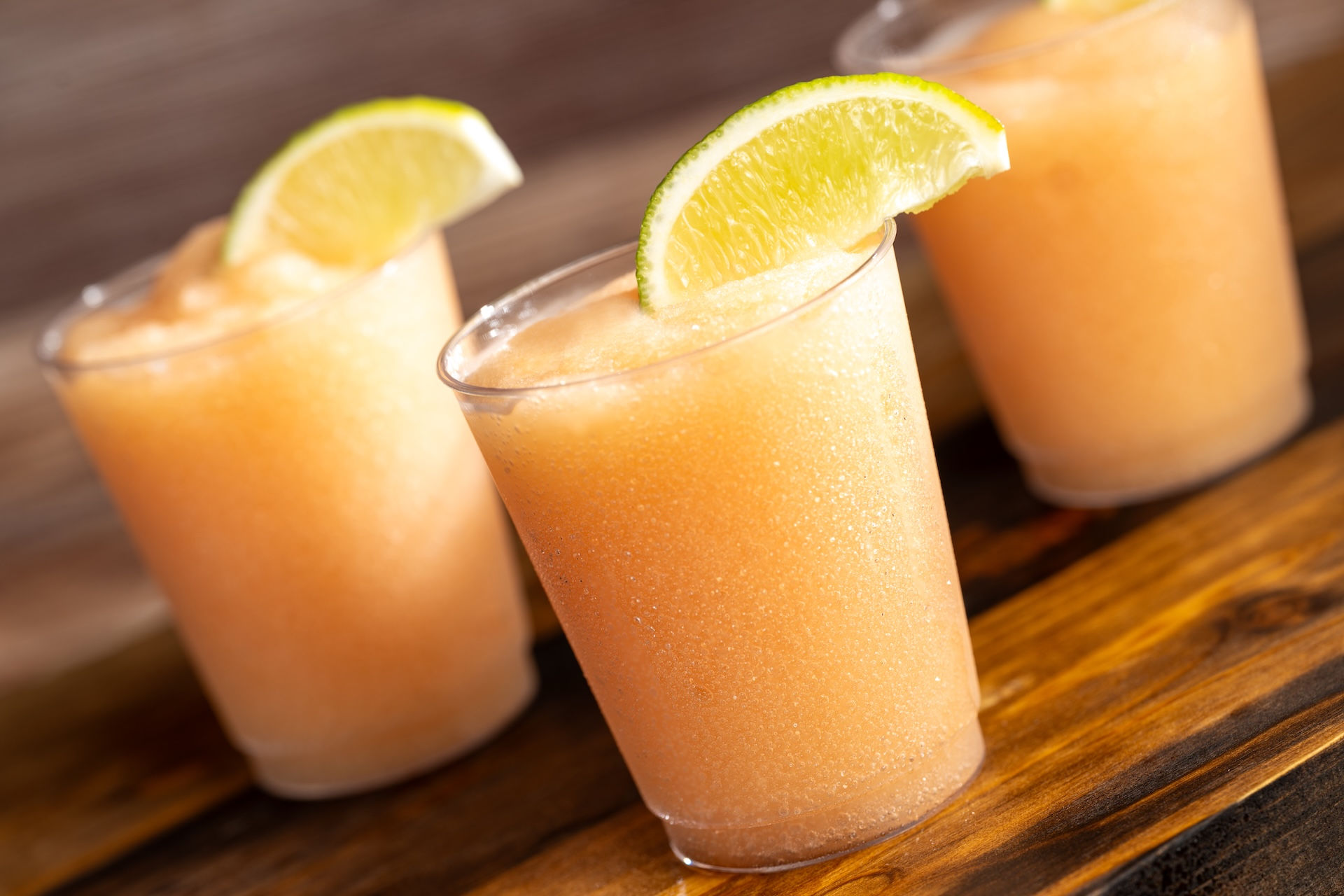 Citrus frozen festival drinks served at EPCOT Flower & Garden Festival Outdoor Kitchen, showcasing refreshing Disney World spring beverages and popular World Showcase festival snacks recommended in a Walt Disney World trip planning guide by Disney specialist Brandi Parker.
