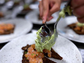 Hånd legger avokadokrem på laksetoast.