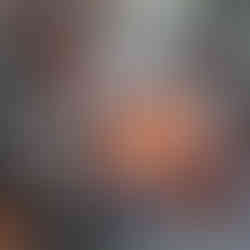 Man cooking food over a campfire, wooden structure, sitting, and boiling water.