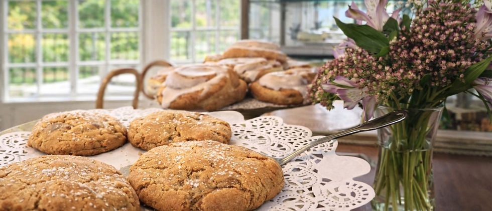Cookies and cinnamon buns on table with flowers