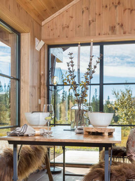 Dekket bord inne i en moderne hytte med store vinduer