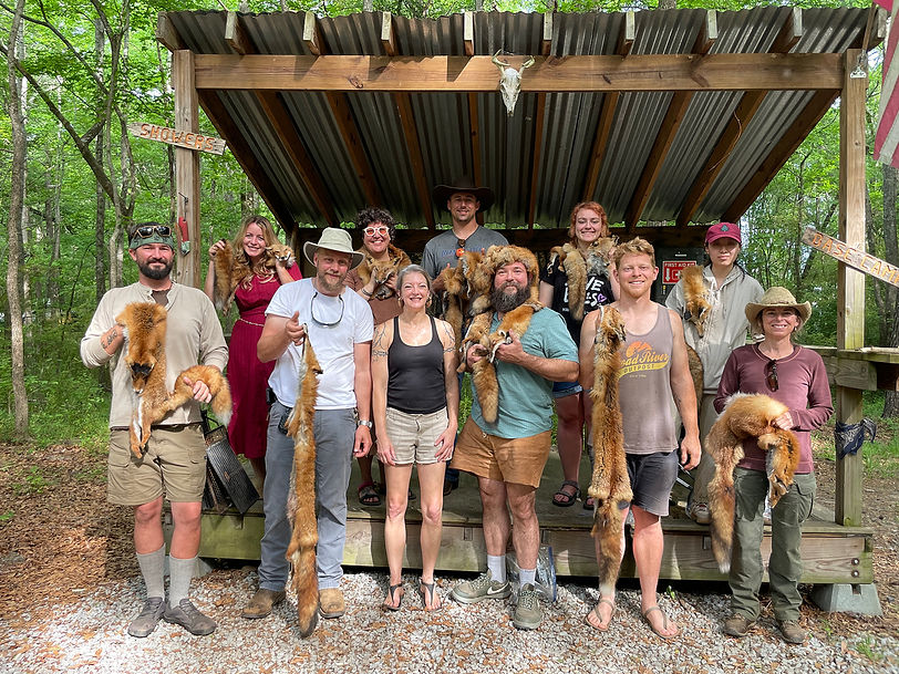 Participants at a hide tanning workshop posing with fox furs.