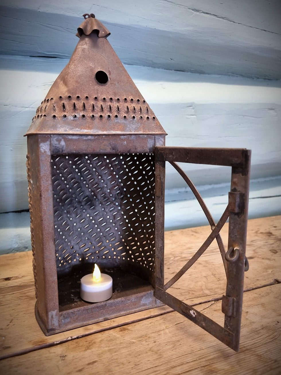 An old rusty metal lantern made of tin with punched shapes and holes with a candle inside
