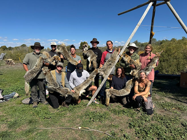 Group of workshop participants displaying animal furs outdoors with Theresa Emmerich Kamper.