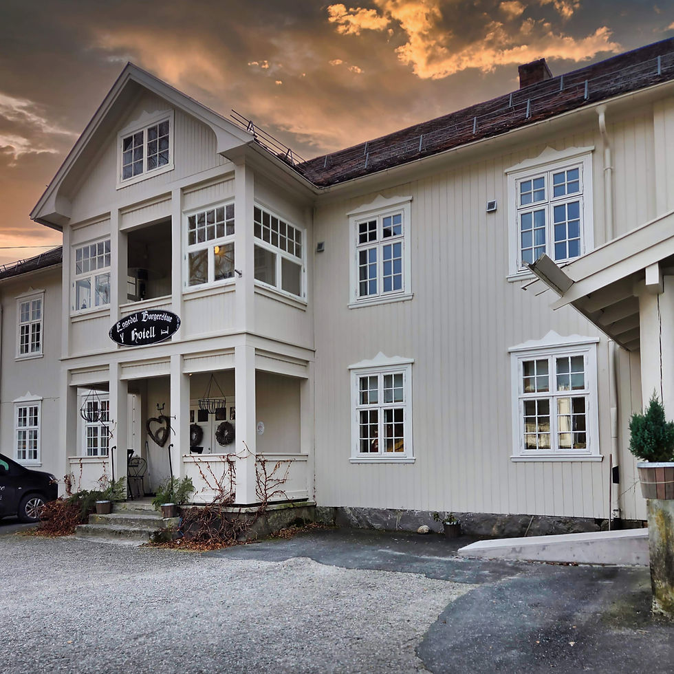 Cream-colored old wooden buidling with a hotel exterior under a vibrant, cloudy sunset sky. A black sign reads "Eggedal Borgerstua."