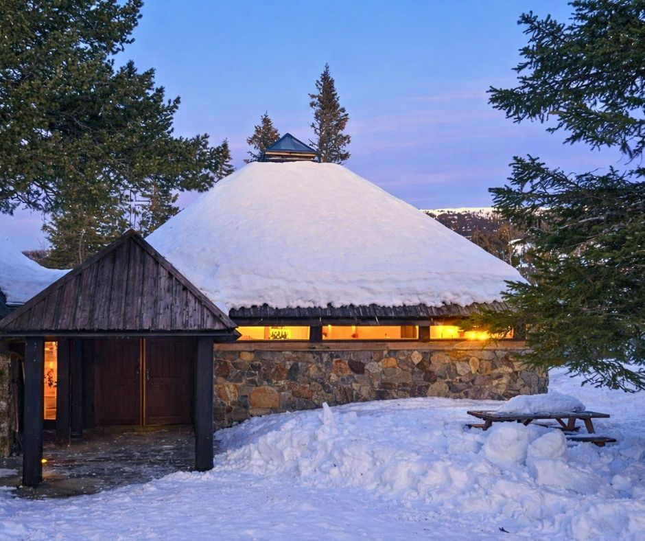 Snow-covered stone building with illuminated windows in winter