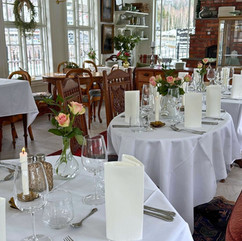Dekkede bord med hvite duker og roser i restaurant