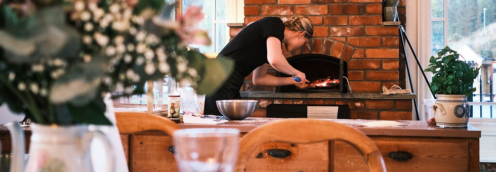 Kokk ved vedfyrt ovn med fjellutsikt