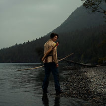 Theresa Emmerich Kamper dressed in leather, holding a bow and looking at the mountains in Canada.