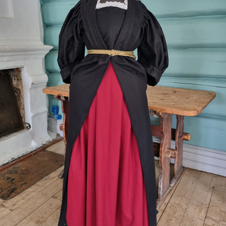 Replica of 18th century dress, and very much like the one Anna Colbjørnsdatter is wearing in a portrait. The dress has a red skrit and a black overcoat with a gold belt.