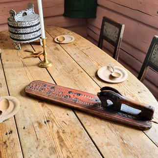 A red painted mangle board lying on a table. The horse handle is carved from the same piece of wood. 