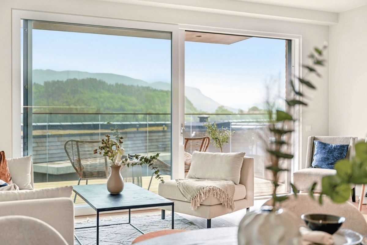 Stue med store skyvedører ut til balkongen og utsikt mot åsene i leilighetstype 5 på Steinsfjorden Terrasse