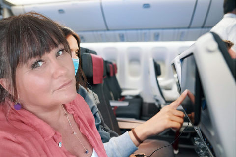 AK Magraff looking out the window of an airplane wearing a red dress.