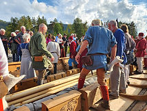 Folk i vikingklær går om bord i vikingskipet Dronning Åsta.