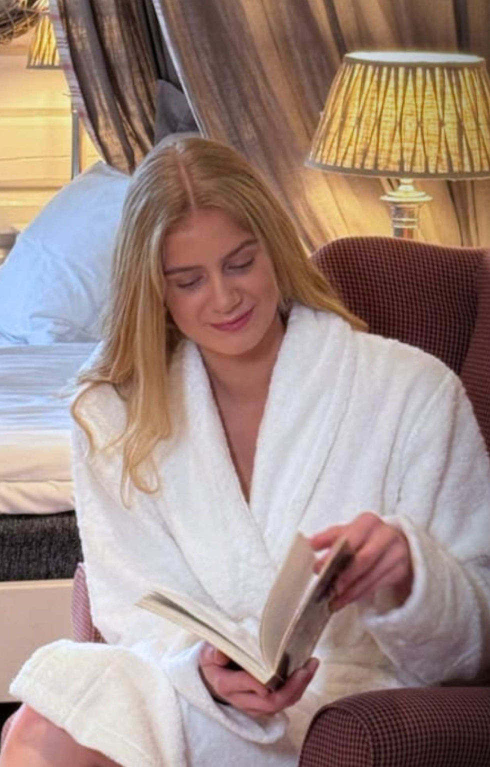 Woman reading book in bathrobe in bedroom