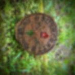 Wooden sign reads Bushcraft Ridge, with arrows and leaf, viewed in grass.