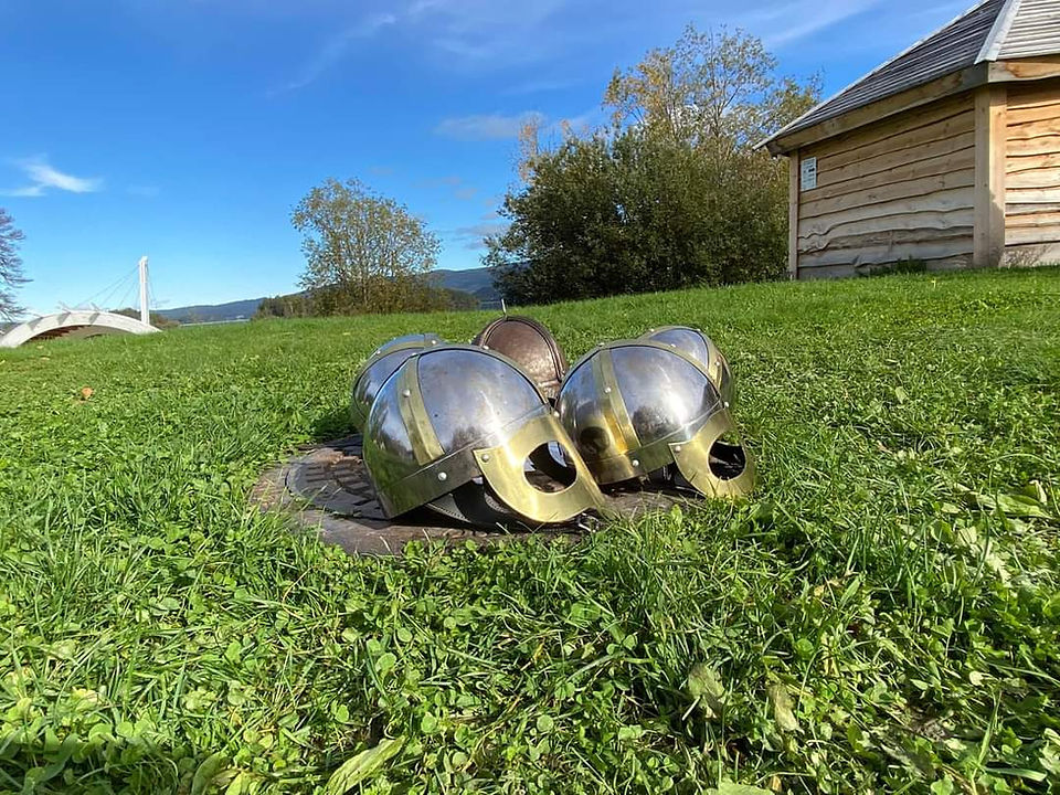 Kopier av Gjermunduhjelmen smidd av Hardraade vises frem på en gressplen. 