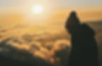 Woman looking down with the clouds and sun in the background
