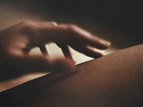Main effleurant la peau dans une lumière douce