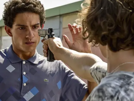 un jeune homme pointe une arme