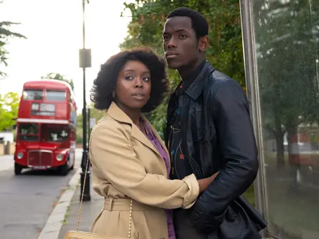 un homme et une femme enlacée devant un bus rouge