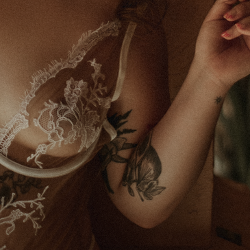 Woman in delicate white lace lingerie, gently holding her hand against her heart and chest.