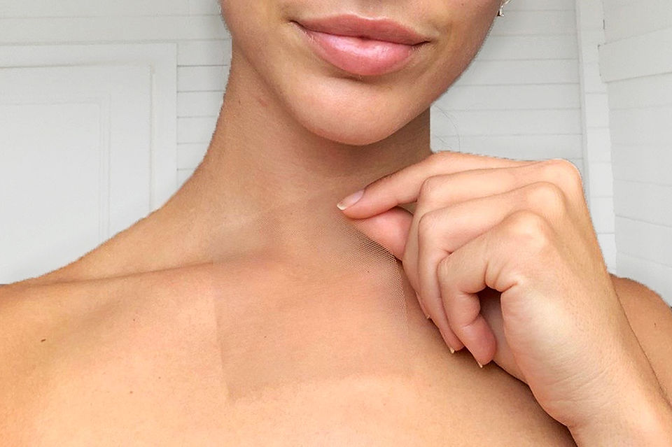 Women holding sheer fabric swatch against her skin. 