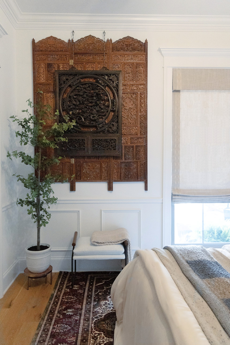 a bedroom with a plant and a carved wall