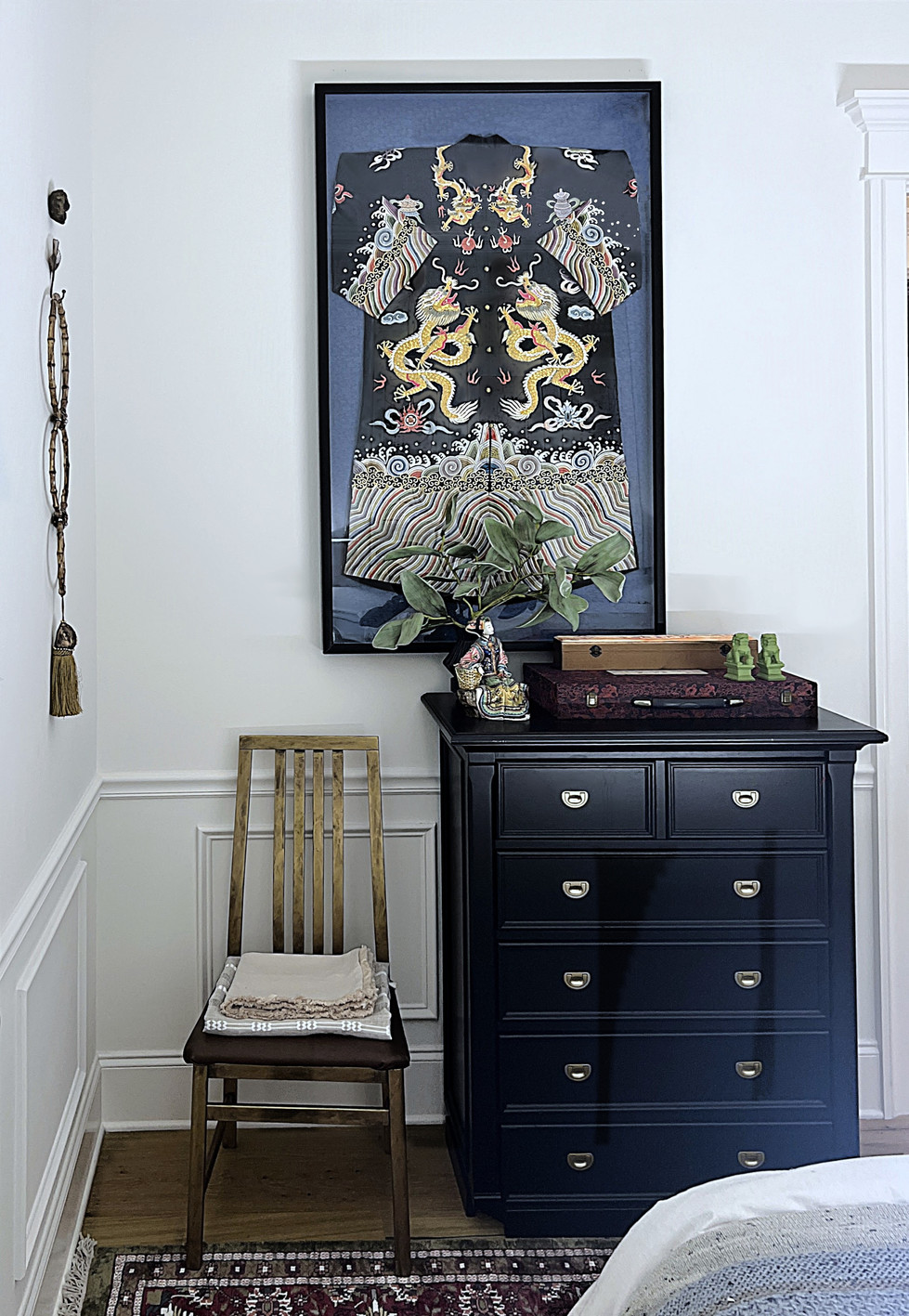 a black dresser with a picture on the wall above it