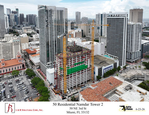 Aerial view of the active construction site for 50 Residential Namdar Tower 2 in downtown Miami, showcasing two tower cranes and the concrete podium structure.
