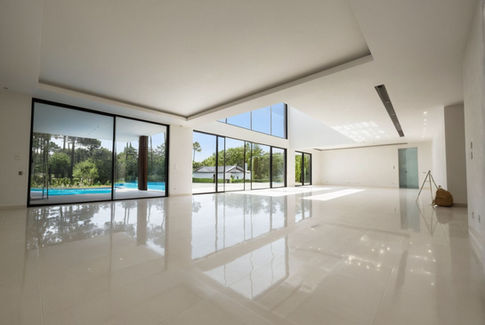 Large open plan room, white porcelain tile floor, floor-to-ceiling sliding glass doors, swimming pool, pine trees, lawn, modern villa,  bright sunlight, summer.