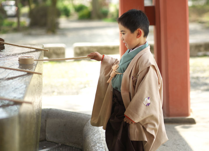七五三の袴姿で神社の手水舎を使う男の子