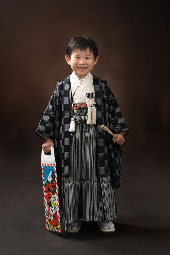 千歳飴を持って微笑む、羽織袴姿の男の子の七五三記念写真