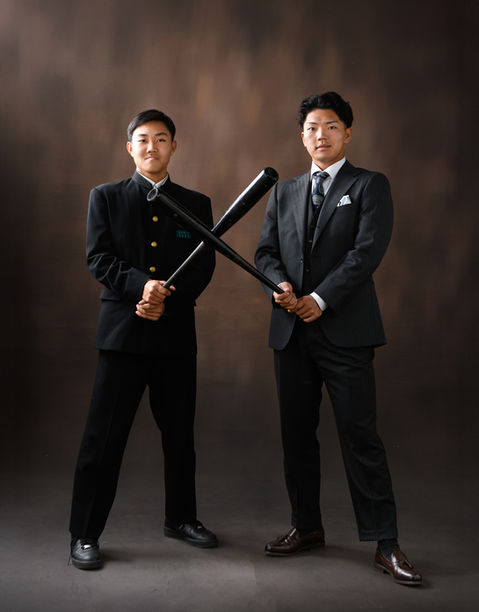 成人式でバットを交差させポーズをとる学生服とスーツの男性